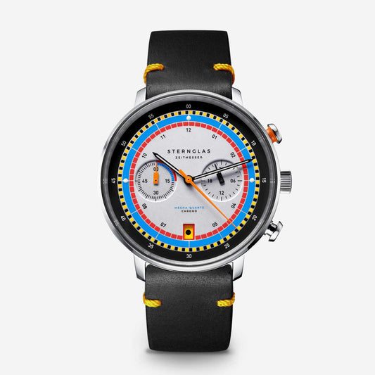 popup|Inspired by regatta chronographs of the 1970s..|..the primary Bauhaus colours of red, yellow and blue meet the colour scheme of sailing boat racing. A special detail awaits sailing fans in the date window: every two days, the colourful signal symbols of the regatta appear instead of the numbers.